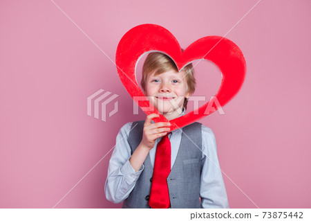 Valentines day. Funny little boy posing with heart on pink background Valentines day. Funny little boy posing with heart on pink background 73875442