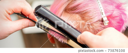 Hairdresser straightening the short hair 73876108