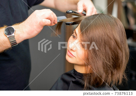 Hairdresser is straightening the hair Hairdresser is straightening the hair 73876113