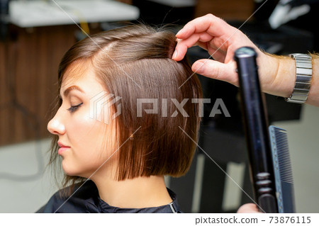 Hairdresser is straightening the hair 73876115