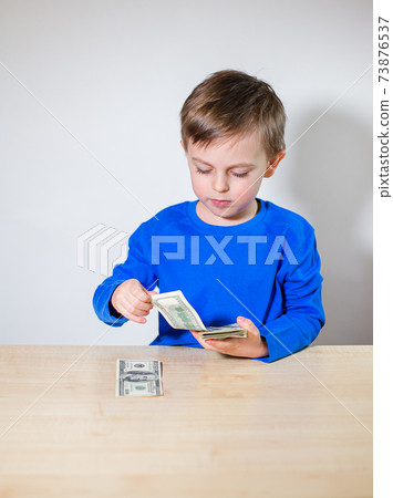 Happy child with money dollar, little businessman. Pile of United States dollar hundred USD banknotes Happy child with money dollar, little businessman. Pile of United States dollar hundred USD banknotes 73876537