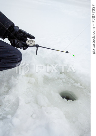 Close up of a ricky fisherman with a fishing rod. Ice and fishing rod for winter fishing. Winter fishing. Small catch of fish. Close up of a ricky fisherman with a fishing rod. Ice and fishing rod for winter fishing. Winter fishing. Small catch of fish. 73877057