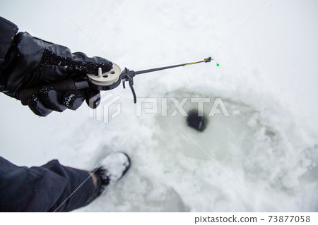 Close up of a ricky fisherman with a fishing rod. Ice and fishing rod for winter fishing. Winter fishing. Small catch of fish. Close up of a ricky fisherman with a fishing rod. Ice and fishing rod for winter fishing. Winter fishing. Small catch of fish. 73877058
