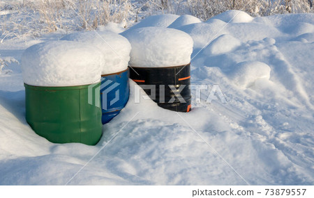 Frozen crumpled red barrel in the snow 73879557