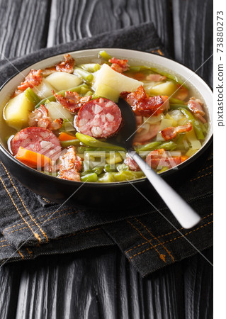Bouneschlupp is a traditional Luxemburgish green bean soup with potatoes, bacon, and onions close-up in a plate. Vertical 73880273