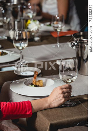 woman holds glass of white wine. people consider the color of the wine and try how it smells in different glasses 73880283