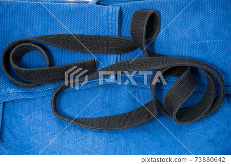 The view from the top. Kimono for judo classes and a black belt. The kimono is blue. Background, texture. The view from the top. Kimono for judo classes and a black belt. The kimono is blue. Background, texture. 73880642