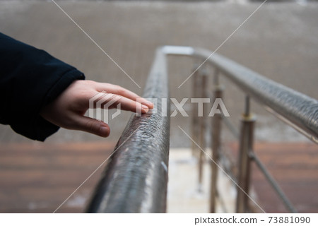 A hand touches the frozen handrails. Freezing rain. Cold season and frost A hand touches the frozen handrails. Freezing rain. Cold season and frost 73881090