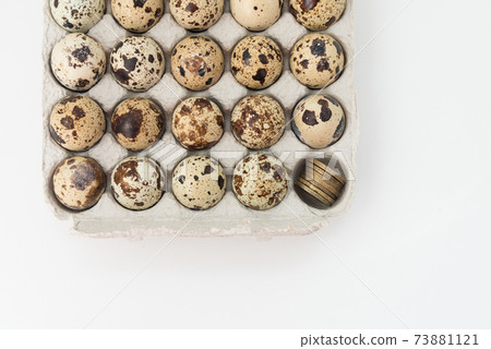 Quail eggs in the egg tray. In one Department, instead of an egg, there are coins. Concept of earnings and expenses in agriculture. 73881121