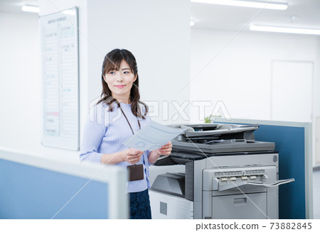 Female employee making a copy in the office Female employee making a copy in the office 73882845