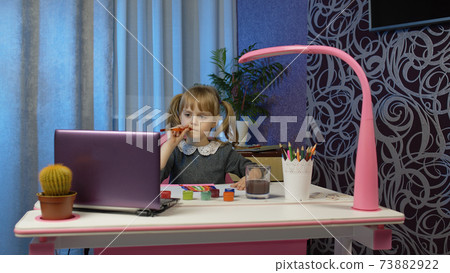 Child girl schoolgirl enthusiastically drawing with brushes and paints, distance education at home Child girl schoolgirl enthusiastically drawing with brushes and paints, distance education at home 73882922