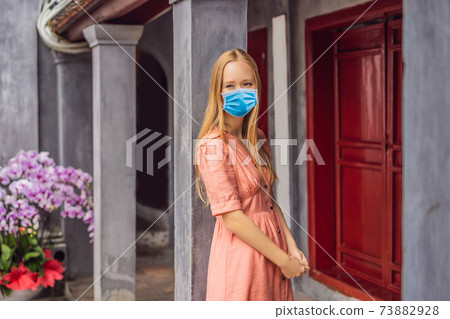 Woman tourist wearing a medical mask during COVID-19 coronavirus on background of Temple Ngoc Son in Hanoi, Vietnam.Temple of Literature is also called temple of Confucius. Vietnam reopens after Woman tourist wearing a medical mask during COVID-19 coronavirus on background of Temple Ngoc Son in Hanoi, Vietnam.Temple of Literature is also called temple of Confucius. Vietnam reopens after 73882928