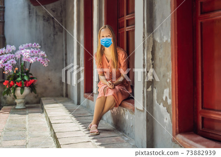 Woman tourist wearing a medical mask during COVID-19 coronavirus on background of Temple Ngoc Son in Hanoi, Vietnam.Temple of Literature is also called temple of Confucius. Vietnam reopens after 73882939
