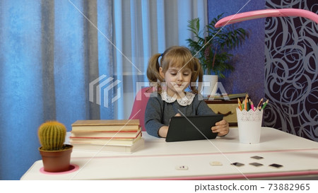 Child schoolgirl learning lessons, distance education at home sitting at table using laptop computer Child schoolgirl learning lessons, distance education at home sitting at table using laptop computer 73882965