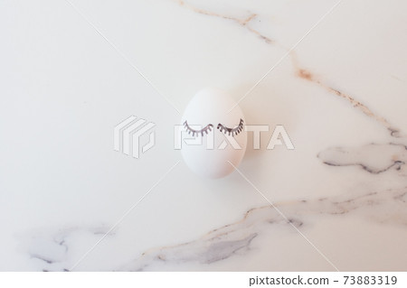 Minimal easter concept white egg and tropical branches with leaves. Stylish Easter white egg on a marble background. The flat lay fashionable easter. Happy easter card with copy space for text Minimal easter concept white egg and tropical branches with leaves. Stylish Easter white egg on a marble background. The flat lay fashionable easter. Happy easter card with copy space for text 73883319