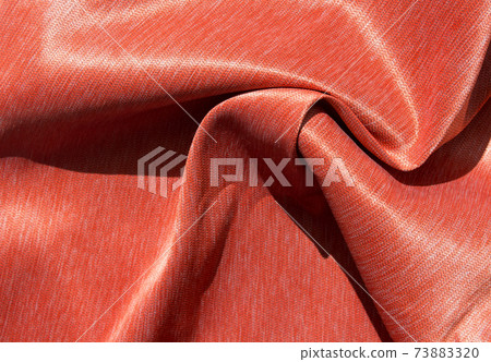 Luxurious expensive orange fabric as an elegant background with beautiful tints of light. Soft folds fall and create light waves 73883320