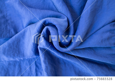 Luxurious expensive blue fabric as an elegant background with beautiful tints of light. Soft folds fall and create light waves Luxurious expensive blue fabric as an elegant background with beautiful tints of light. Soft folds fall and create light waves 73883328