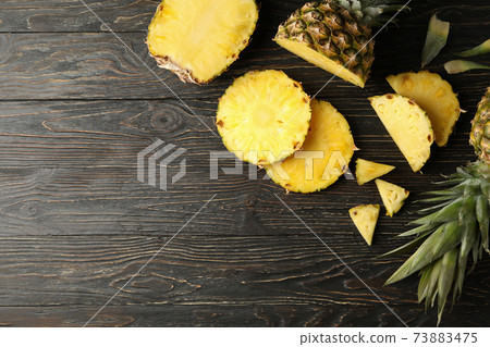 Ripe pineapples and slices on wooden background, top view 73883475