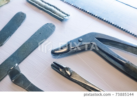 Old surgical metal medical devices on wooden table 73885144