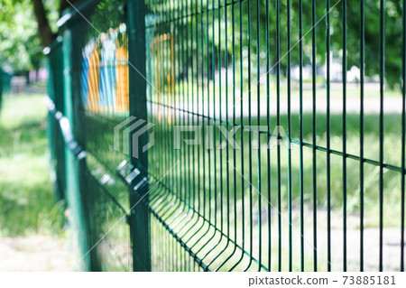 A blue mesh fence close up in summer 73885181