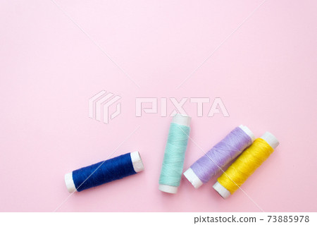 Colored sewing thread on a pink background 73885978