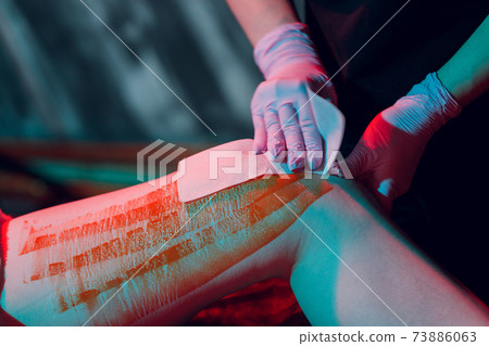Mid section of therapist waxing woman's leg at spa center. Mid section of therapist waxing woman's leg at spa center. 73886063