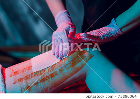 Mid section of therapist waxing woman's leg at spa center. Mid section of therapist waxing woman's leg at spa center. 73886064
