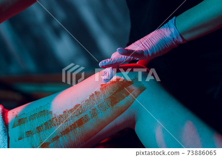 Mid section of therapist waxing woman's leg at spa center. Mid section of therapist waxing woman's leg at spa center. 73886065