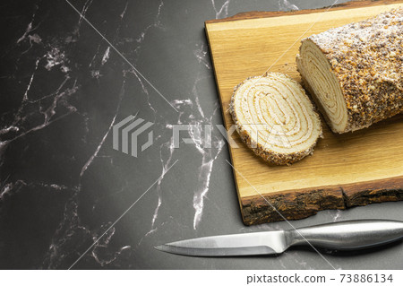 pastry roll on a wooden Board on black marble 73886134