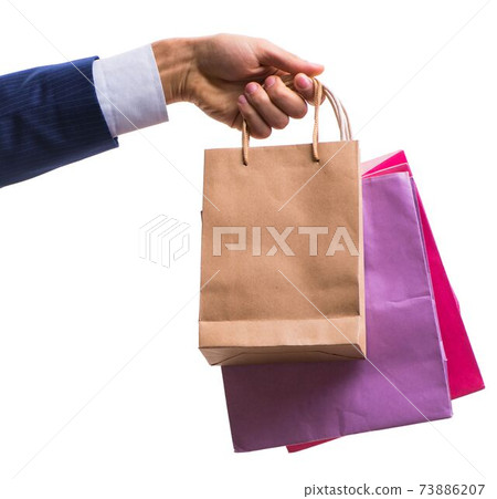 Hand holding shopping bags with christmas shopping on white back Hand holding shopping bags with christmas shopping on white back 73886207