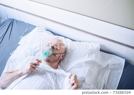 Coronavirus sick man breathing with oxygen mask. Patient in hospital. Coronavirus sick man breathing with oxygen mask. Patient in hospital. 73886504