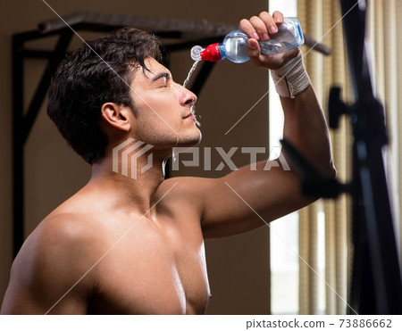 Thirsty man drinking water in sports gym 73886662