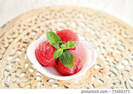 Berry ice cream with mint leaf. three balls in a white bowl on a vintage table. sorbet Berry ice cream with mint leaf. three balls in a white bowl on a vintage table. sorbet 73888373