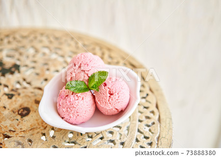 Strawberry ice cream with mint leaf. three balls in a white bowl on a vintage table. sorbet 73888380