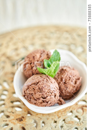 Chocolate ice cream with mint leafe. three balls in a white bowl on a vintage table. Chocolate ice cream with mint leafe. three balls in a white bowl on a vintage table. 73888385
