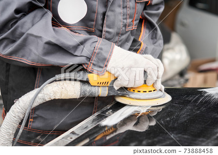 The mechanic works with a grinding tool. Sanding of car elements. Garage painting car service. Repairing car section after the accident. The mechanic works with a grinding tool. Sanding of car elements. Garage painting car service. Repairing car section after the accident. 73888458