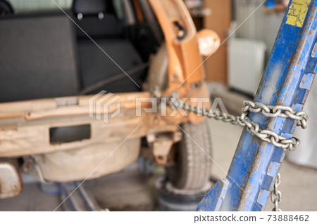 A broken car with a violation of geometry is on the stocks for leveling. Restoration of vehicles with chain and hook. Repair in the workshop and auto 73888462