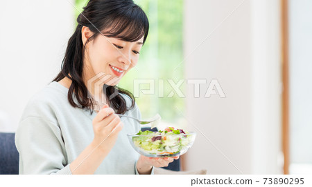 Middle-aged woman eating a salad 73890295