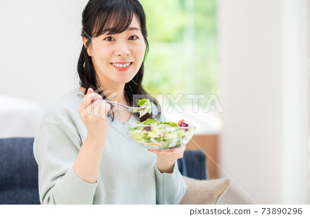 Middle-aged woman eating a salad 73890296