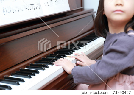 5-year-old girl playing an upright piano 73890407