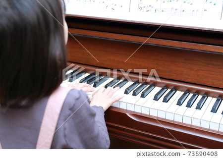 5-year-old girl playing an upright piano 73890408