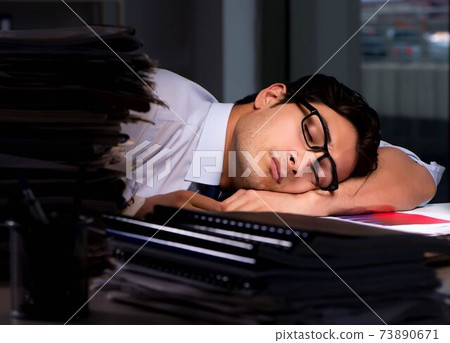 Young businessman working overtime late in office Young businessman working overtime late in office 73890671