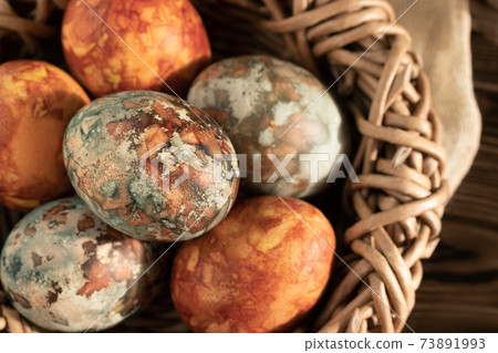 Easter eggs painted with natural dyes in a wicker nest 73891993