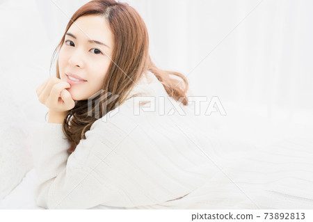 Young woman lying on the bed with her elbows 73892813