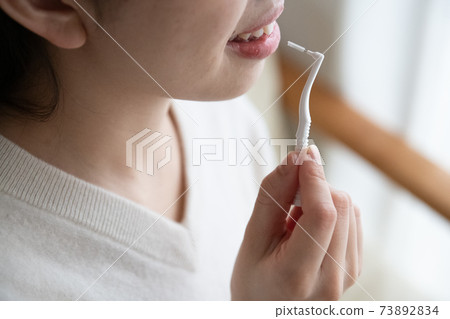 A woman's mouth using an interdental brush 73892834