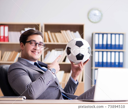 Businessman with football ball in office 73894510