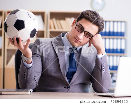Businessman with football ball in office 73894523