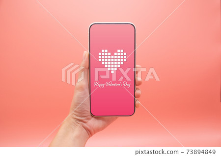 Women hand use smartphone with heart and valentine day screen on pink background, Valentine day concept. Women hand use smartphone with heart and valentine day screen on pink background, Valentine day concept. 73894849