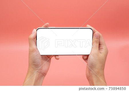 Hand woman holding mobile smartphone with blank screen isolated on pink background, close-up hand touching phone isolated on pink,mock-up smartphone blank screen easy adjustment . Hand woman holding mobile smartphone with blank screen isolated on pink background, close-up hand touching phone isolated on pink,mock-up smartphone blank screen easy adjustment . 73894850