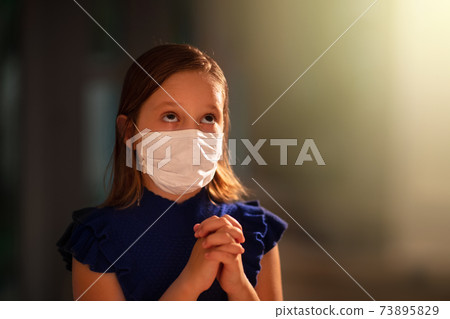 Girl in face mask praying for coronavirus victim Girl in face mask praying for coronavirus victim 73895829